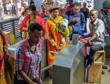 women and men move through dar es salaam brt- DART- station turnstyle