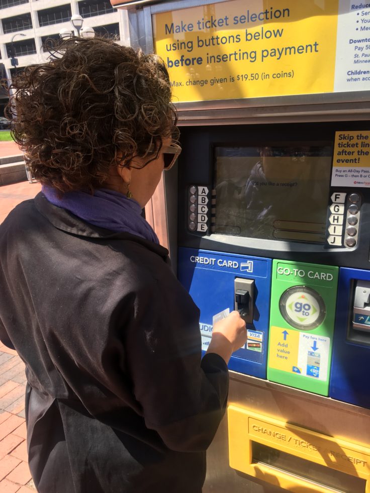 Woman with curly hair buying light rail ticket at Minneapolis tram station