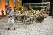 São João Festival dancers in striped outfits and women wearing hats decorated with fruit
