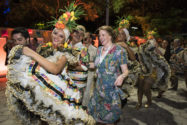 Redhaired woman in blue floral dress in dancing procession with traditional Brazilian dancers