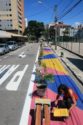 Woman painting a protected pedestrian area with bright pink, blue, and yellow