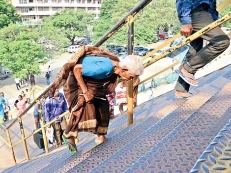 Elderly woman struggling to climb steep pedestrian bridge