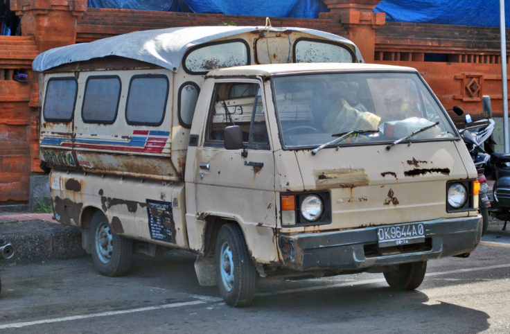 Old angkot, or minibus, with rusted side and rumpled roof